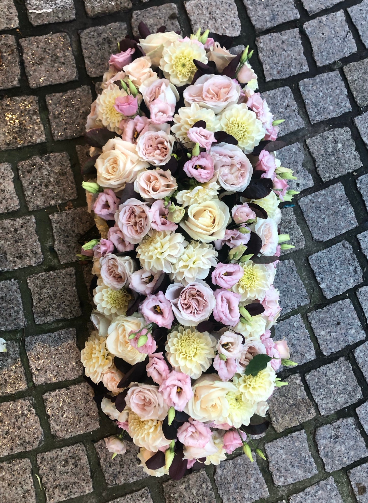 Langwerpig bloemstuk met afgeronde hoeken (60㎝) voor bij Allerheiligen op het graf te leggen. In zachte pasteltinten lila en crème wit. Gevuld met rozen en lisianthius