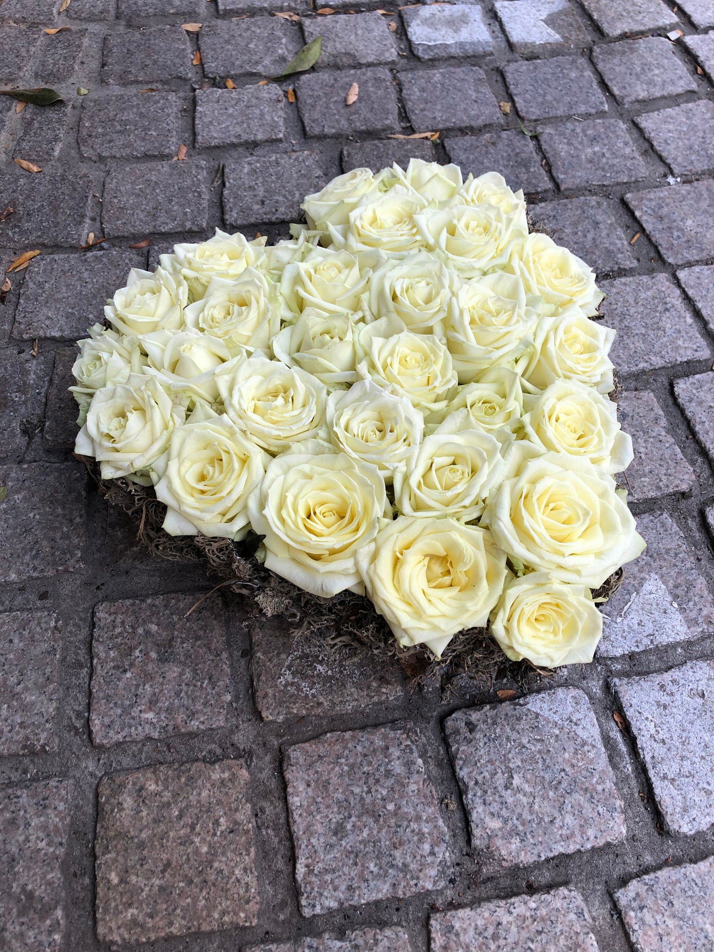Allerheiligen bloemstuk in vorm van een hart opgevuld met witte rozen