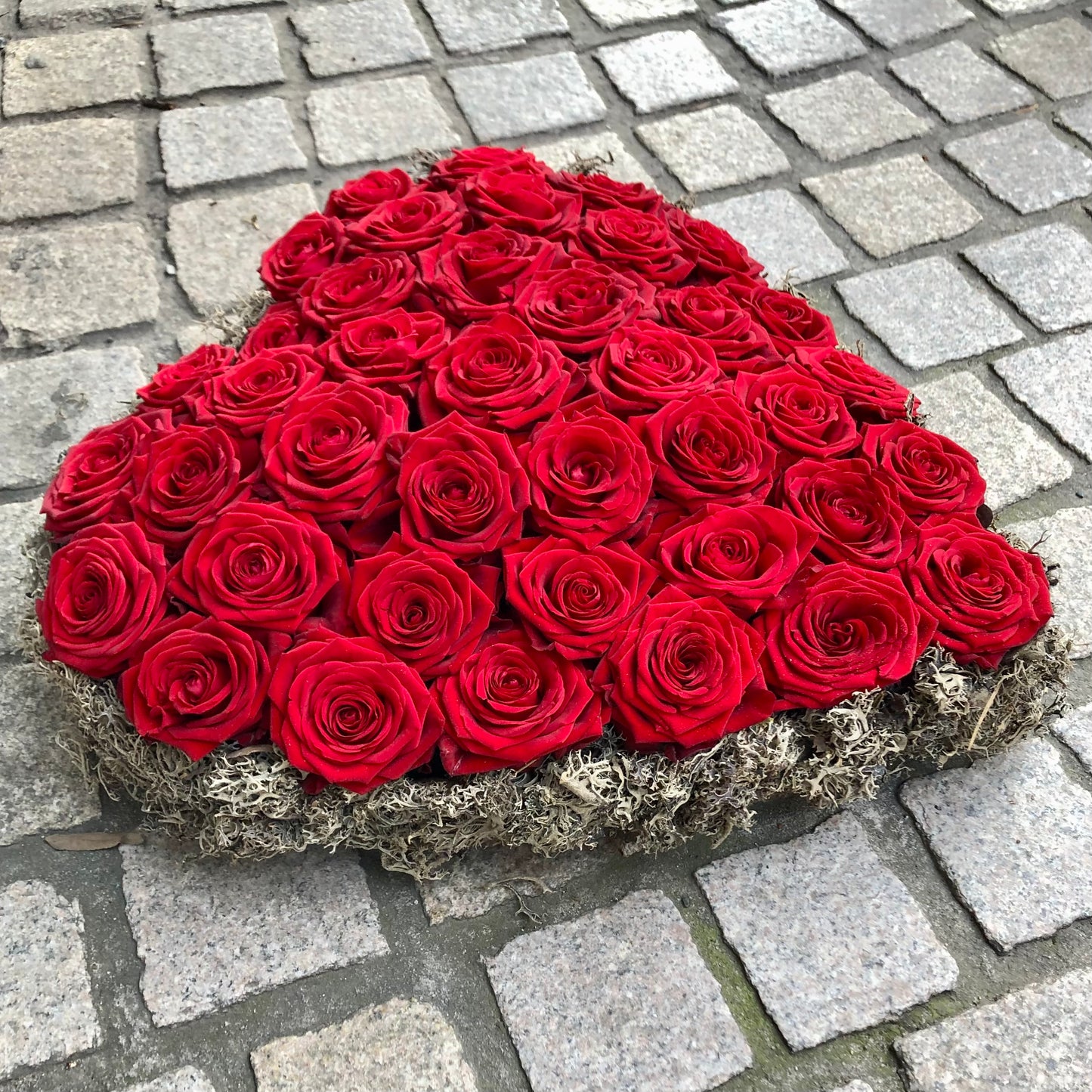 Allerheiligen bloemstuk in vorm van een hart opgevuld met rode rozen