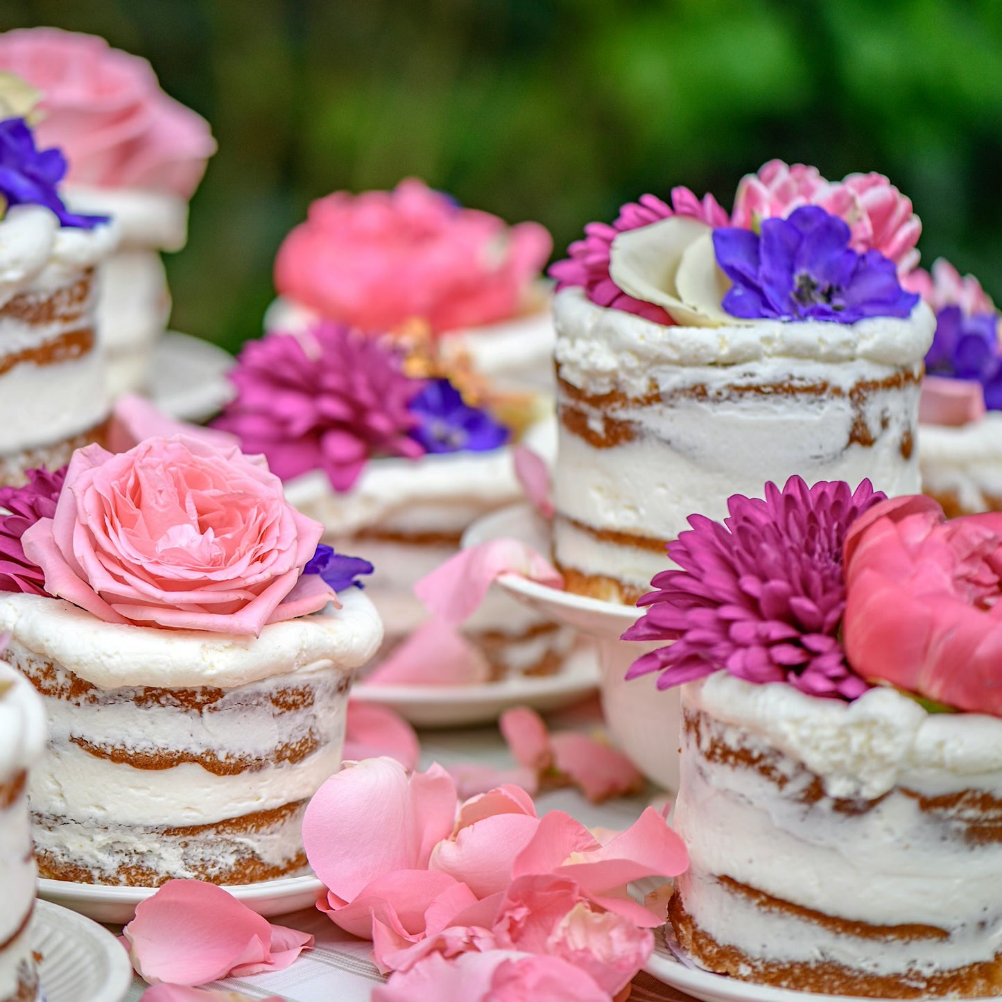 Licht vanille taartjes met mascarpone topping gedecoreerd met prachtige fel roze en blauwe bloemen