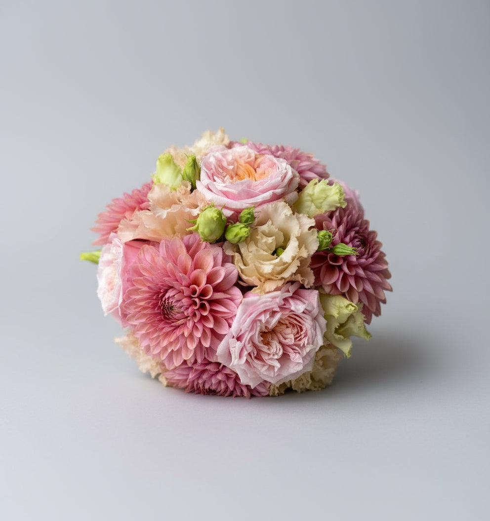 Rond gebonden bloemstuk met dicht op elkaar gestoken rozen, dahlia's of chrysanten en lisianthussen