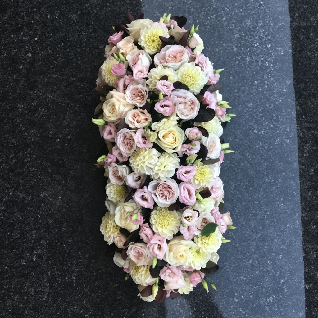 Het bloemstuk van 60 cm bevat Rozen in crème-wit en antiekroze tinten, Dahlia’s in warme pastelkleuren en Lisianthus met hun delicate, klokvormige bloemblaadjes.