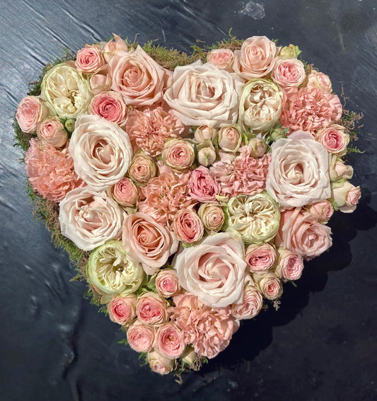 Allerheiligen bloemstuk in vorm van een hart opgevuld met verschillende soorten tuinrozen in zachtroze tinten