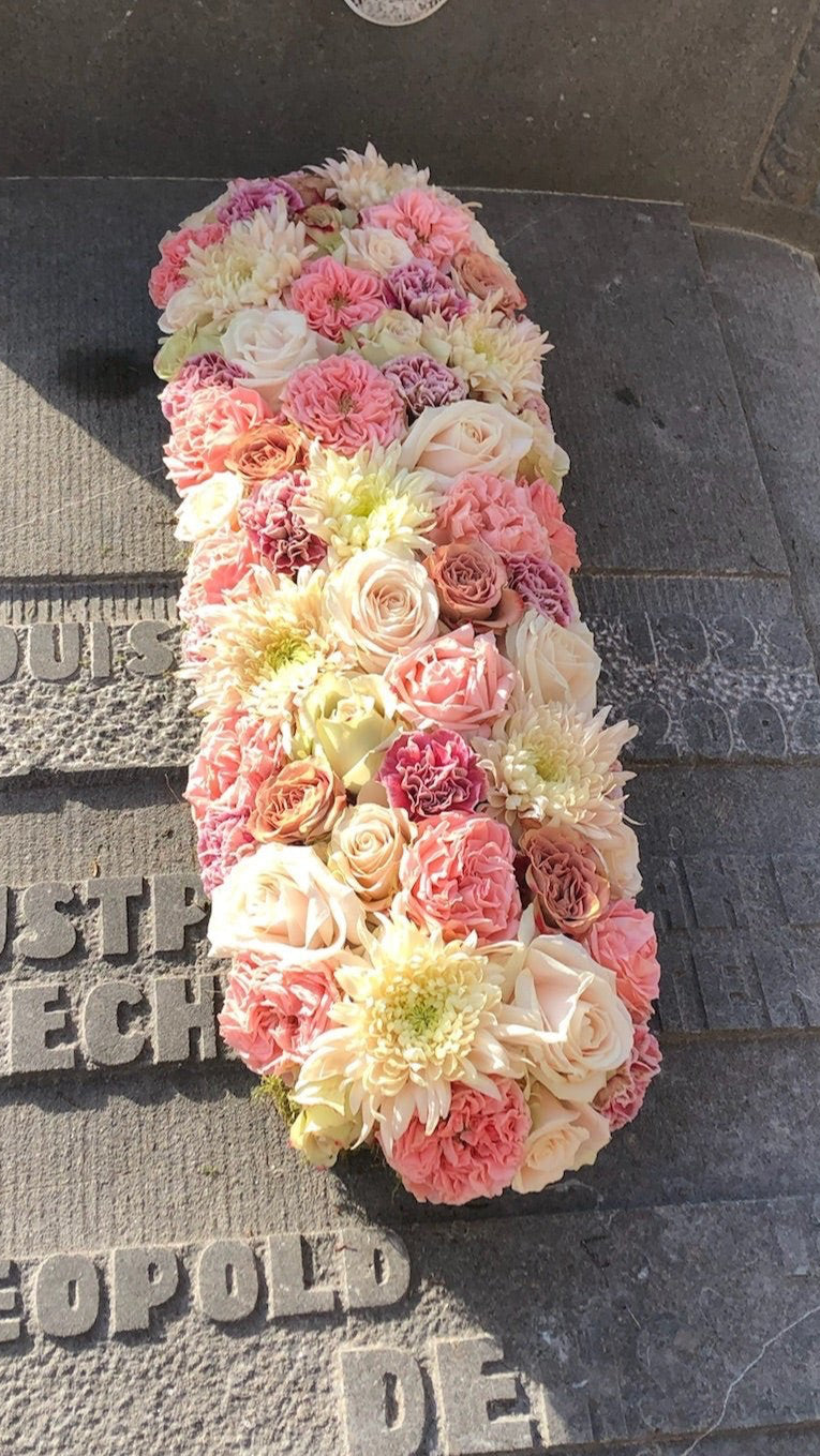 Langwerpig afgerond grafstuk voor Allerheiligen in zachte pasteltinten van een bloemen mix zoals rozen, chrysanten, anjers, tuinrozen
