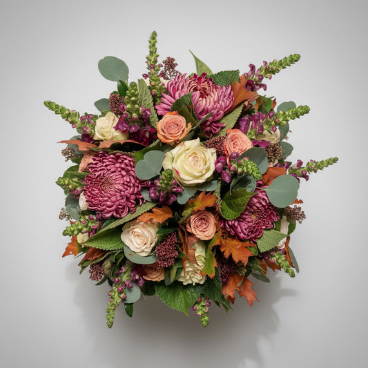 Rond bloemstuk voor Allerheiligen in herfsttinten.