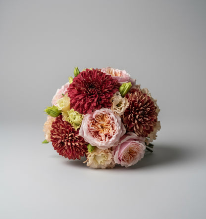 Dicht opklaar gestoken rond gebonden bloemstuk in warme kleuren