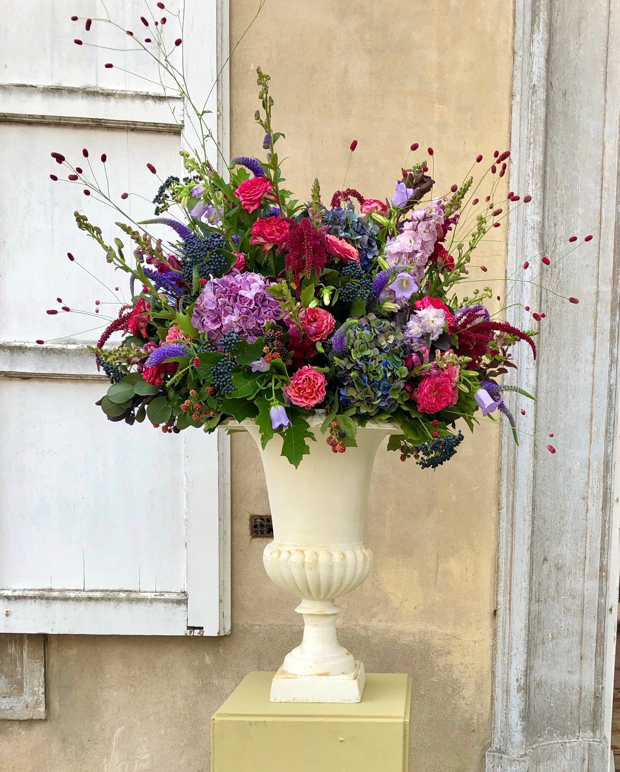 Klassiek bloemstuk in antieke vaas met roze rozen, paarse hortensia's en groene accenten voor luxe evenement