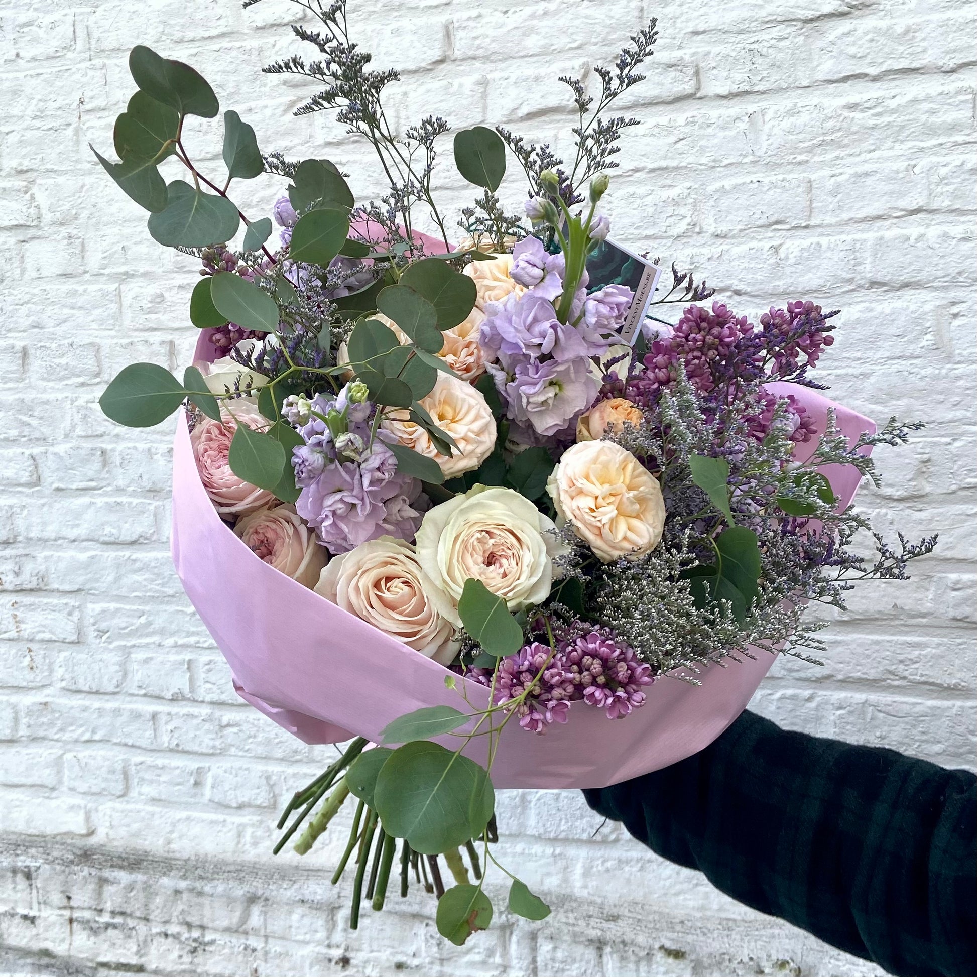 Groot en goed gevuld romantisch boeket in pastel tinten kleuren gevuld met verschillende soorten tuinrozen, seringen en eucalyptus 